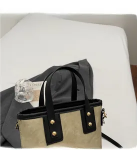 Detalle de bolso de lona con adornos de cuero negro y remaches metálicos dorados