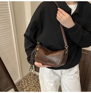 Close-up of vintage brown PU leather crossbody bag with woven cord and gold hardware