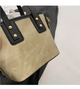 Detalle del bolso de lona de sarga caqui con ribete de cuero negro y remaches dorados