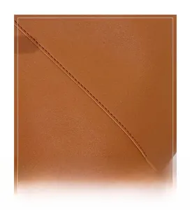 Close-up detail of the premium brown leather texture and precise stitching on the tote bag