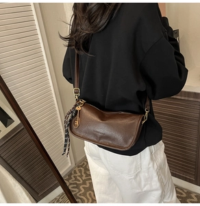 Detail of dark brown leather crossbody bag with decorative tennis racket pendant