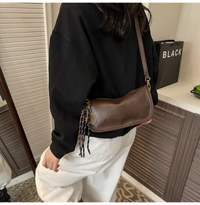 Detail of coffee brown crossbody bag with tennis racket charm and tassel ornament