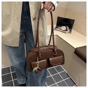 Detailed view of brown faux suede shoulder bag featuring cherry charm and front pockets