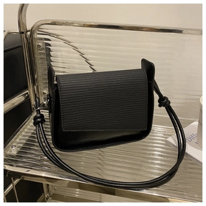 Close-up of black PU leather shoulder bag with textured flap and stylish knot strap detail