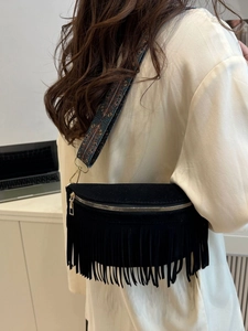 Vintage black fringed crossbody bag with colorful jacquard strap shown in a lifestyle setting