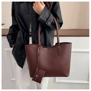 Detail view of large dark brown tote bag with leather texture and matching envelope pouch