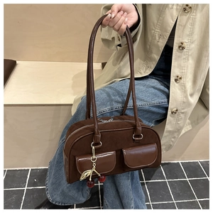 Close-up of vintage brown suede shoulder bag with dual pockets and cherry charm