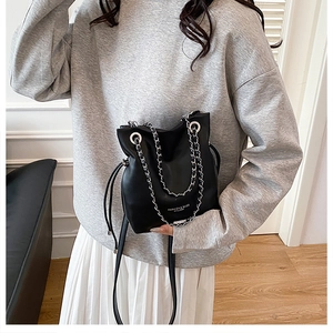 Detailed view of black bucket bag with silver chain strap and drawstring closure