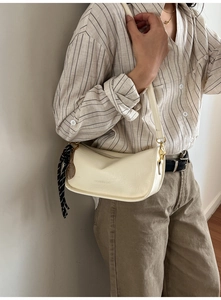 Detail of hobo bag with gold tennis racket charm and black white striped silk scarf