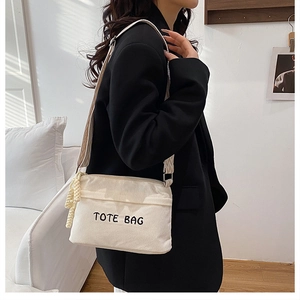 Detail of corduroy tote bag featuring TOTE BAG embroidery and woven shoulder strap