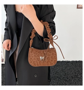 Detail of leopard print underarm bag with silver butterfly buckle and pleated strap