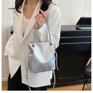 Close-up of metallic silver chain bucket bag with drawstring and fashion text detail