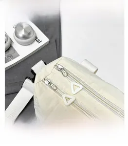 Detail view of smooth double zippers and plastic pull tabs on a cream canvas handbag