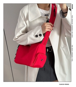 Detalle de bolso bandolera de nailon rojo con bolsillo frontal y correa ancha