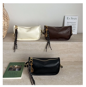 Detailed view of leather cross-body bags in cream, brown, and black with tassel charms
