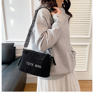Detail showing the white TOTE BAG embroidery on black corduroy fabric and geometric strap