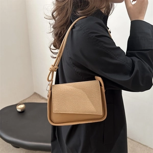 Minimalist caramel leather underarm bag with striped embossing and knotted strap on model