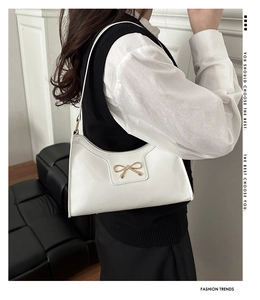 Gros plan d'un sac à bandoulière en cuir verni blanc avec fermoir nœud en métal doré