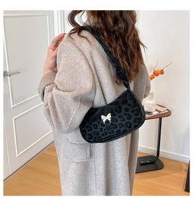 Detail of leopard print shoulder bag featuring a silver butterfly buckle and ruched strap