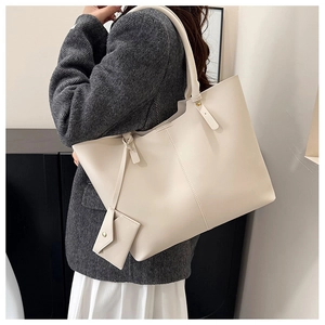 Detail of a creamy white large tote bag with matching pouch on model in a suit