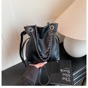 Detailed close-up of a black leather bucket bag with silver chain strap and logo