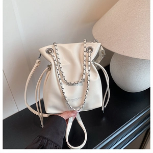 Close-up of cream bucket bag with silver chain handle and drawstring closure