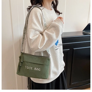 Detail of dark green corduroy tote bag featuring white embroidery and woven strap