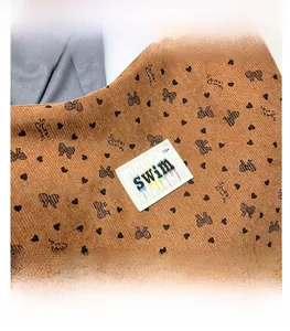 Detail of SWIM logo tag on brown corduroy bag with heart and bow patterns