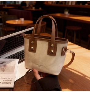 Détail du sac seau en toile avec bordure en cuir marron et garniture métallique dorée