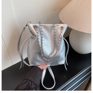 Detail of silver metallic drawstring bucket bag with chain strap and shiny leather finish