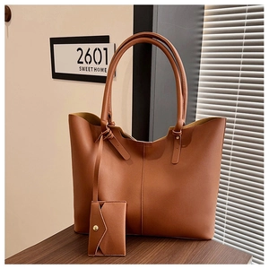 Detailed view of dark brown leather tote bag with vertical stitching and card holder charm