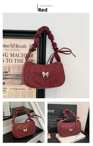 Close-up of wine red suede bag featuring a pleated strap and silver butterfly metal detail