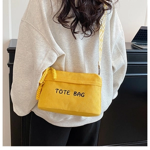 Detail of yellow corduroy tote bag with embroidered letters and patterned wide strap
