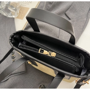 Détail du sac à main contrasté avec bordures en cuir noir et fermeture éclair dorée élégante