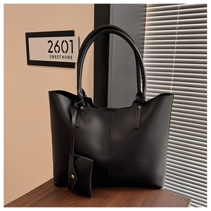 Close-up of black leather tote bag featuring fine stitching and a gold rivet detail