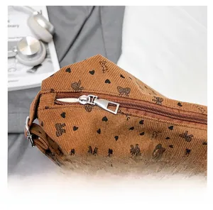 Detail view of the smooth silver zipper and heart print on brown corduroy bag