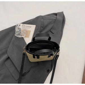 Vue à plat d'un sac seau en daim vert olive avec lanières en cuir noir et zips dorés