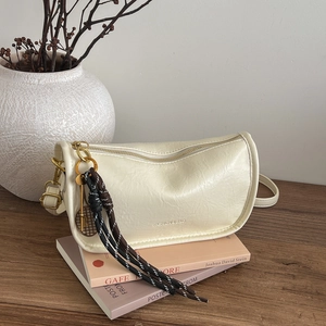 Retro cream white cylindrical shoulder bag with gold chain and woven charm on desk