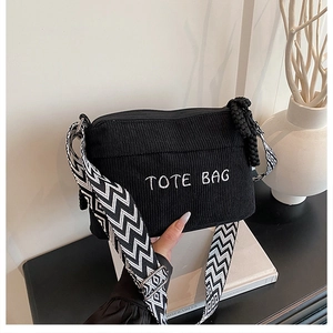 Detail of black corduroy tote bag featuring white embroidery and geometric pattern strap