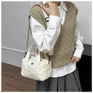 Detail of a casual canvas bag with top handles, adjustable strap and round logo