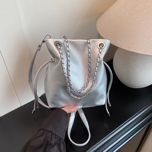 Modern silver bucket bag with woven chain handles and metallic finish for daily style