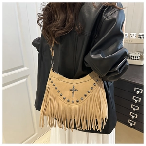 Détail du sac en daim marron avec rivets métalliques, décor croix et longues franges