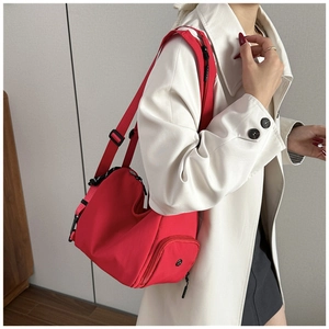 Detalle de bolso bandolera de nailon rojo con correa ajustable y bolsillo lateral con cremallera