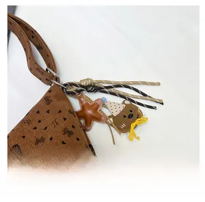 Detail of corduroy bag with heart print and cute plush bear star charms attached
