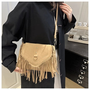 Detail of bohemian fringe bag with rivets and metal ring on khaki suede finish