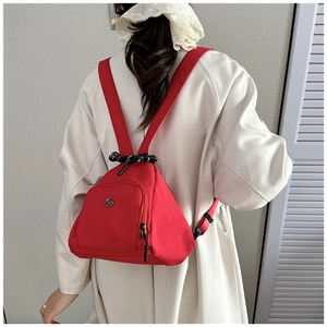 Detalle de la mochila triangular roja de nylon con bolsillo con cremallera y asa trenzada