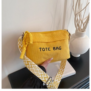 Detail of yellow corduroy tote bag with TOTE BAG embroidery and geometric woven strap