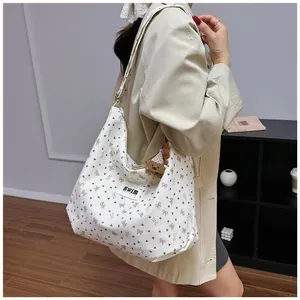 Detail of white corduroy tote bag featuring brown heart prints and bear plush charm