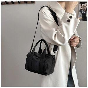 Washed canvas cylinder crossbody bag shown on model wearing a trench coat