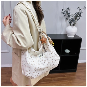 Detail of corduroy tote bag with floral heart patterns and ethnic woven pendant charm
